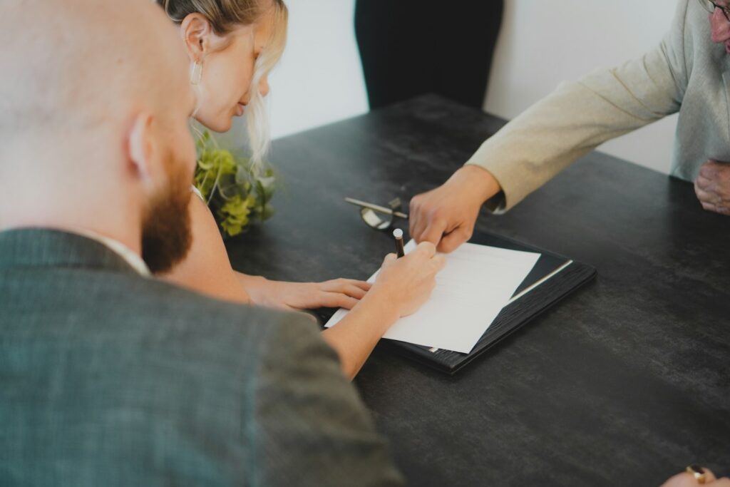 米国不動産の共有名義(夫婦・親子):Joint Tenancy vs Tenancy in Common、贈与税・相続時の扱い couple signing document at desk