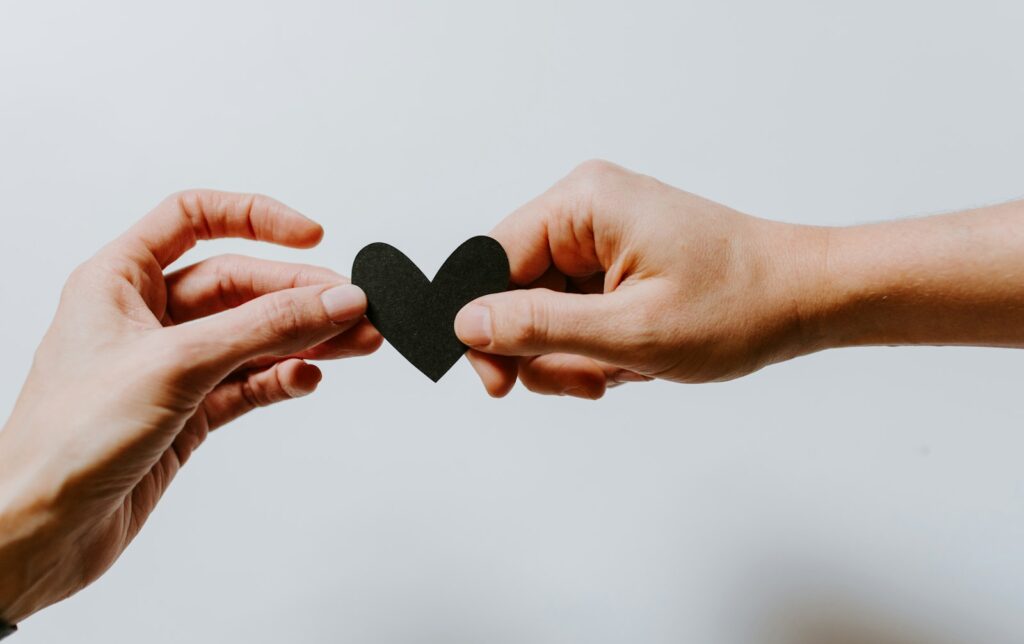 Two people holding a paper-cut heart, representing charitable giving