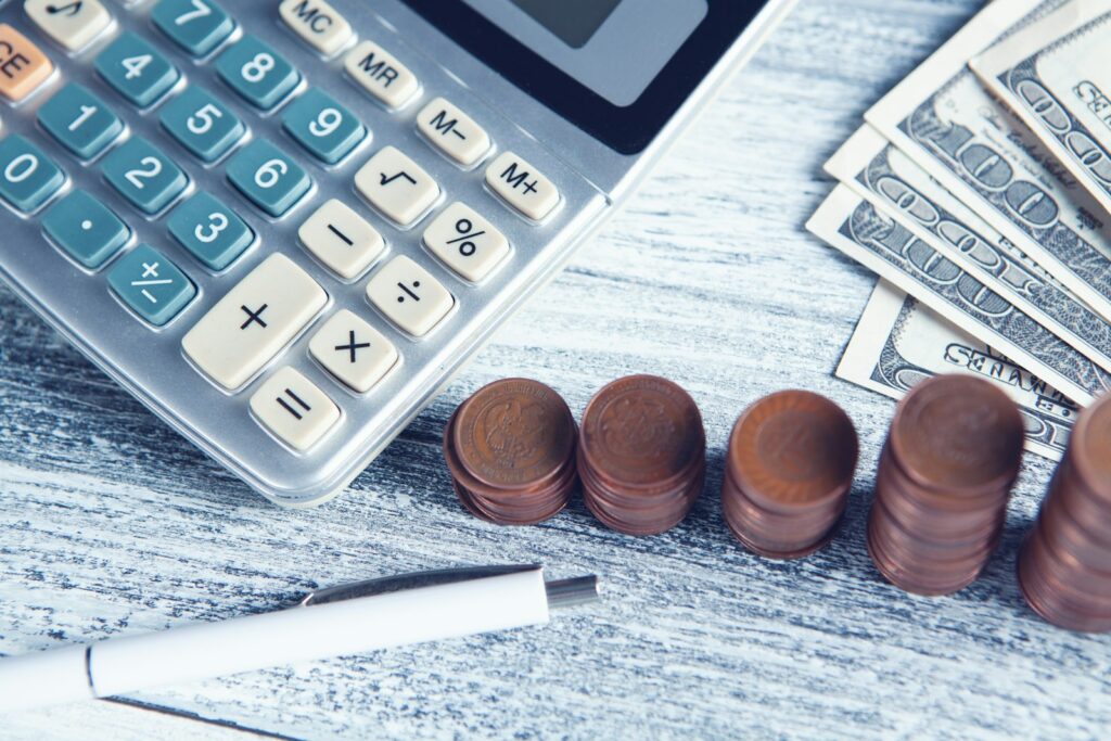 A calculator, a pen, and cash on a table